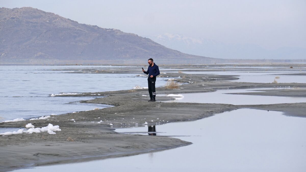 Ruben Gyoeltsyan walks across a sand bar at the receding edge of the Great Salt Lake, Thursday, March 3, 2022, near Salt Lake City. Utah lawmakers passed a $40 million proposal through the state Senate that would pay water rights holders to conserve and fund habitat restoration to prevent the lake from shrinking further. (AP Photo/Rick Bowmer)