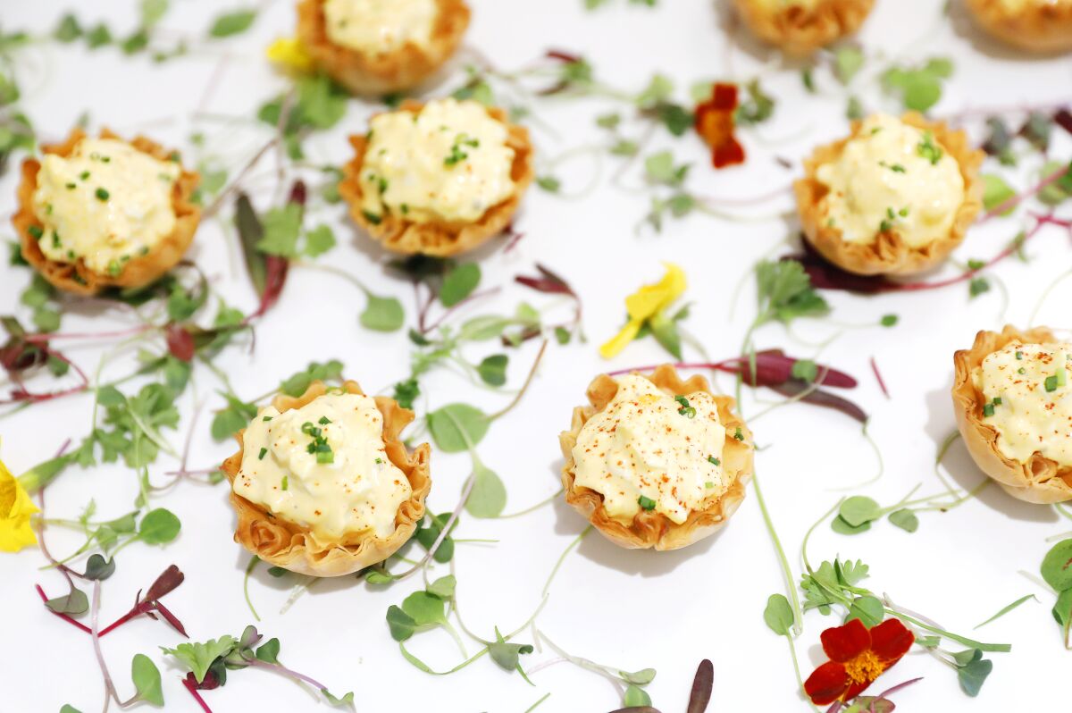 An overhead image shows deviled egg salad in phyllo cups topped by micro greens. 