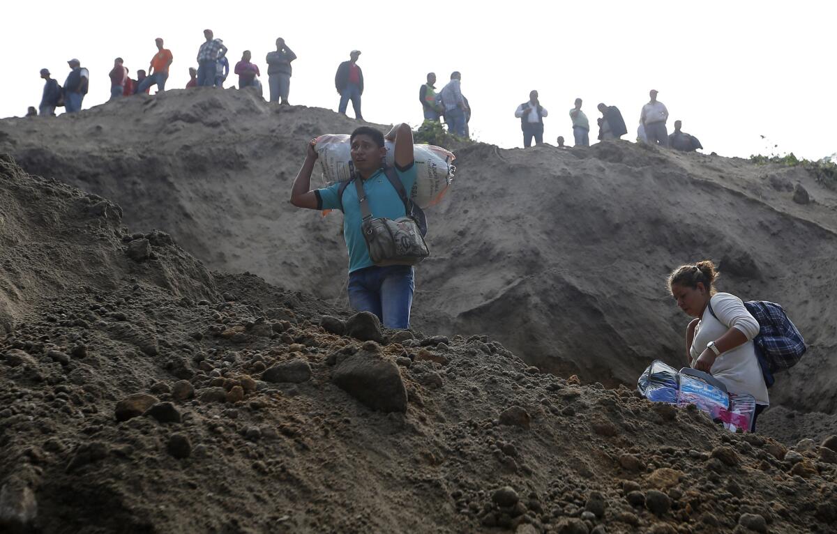Residentes parten mientras prosiguen los trabajos de búsqueda y rescate después de un alud en Santa Catarina Pinula, en las afueras de Ciudad de Guatemala.
