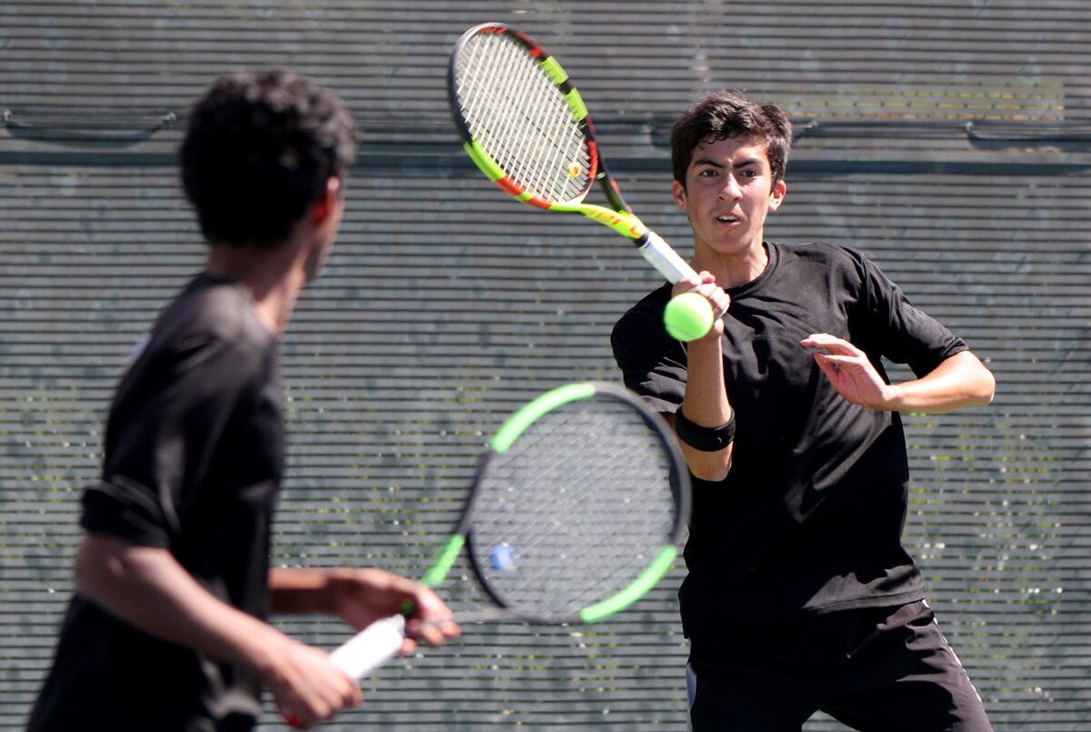 Huntington Beach’s Daniel Izmirian, right, returns the ball as partner Sebastian Vethan looks on in the first round of the CIF Southern Section Individuals doubles tournament against Claremont at Seal Beach Tennis Center on May 22, 2019.