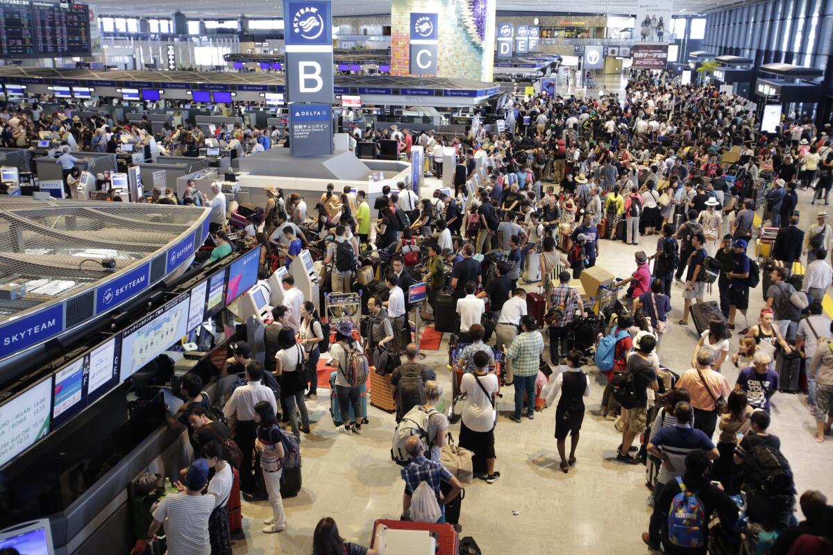 Passengers line up at the Delta Air Lines counter at Narita International Airport east of Tokyo on Tuesday. More than 1,000 people spent the night at the airport because of Monday's computer shutdown that continued to disrupt Delta flights Tuesday.