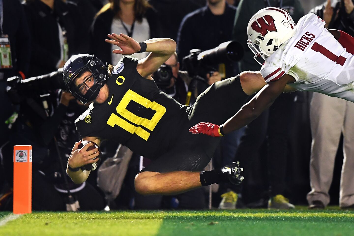 Oregon quarterback Justin Herbert scores the go-ahead touchdown in front of Wisconsin cornerback Faion Hicks during the fourth quarter.