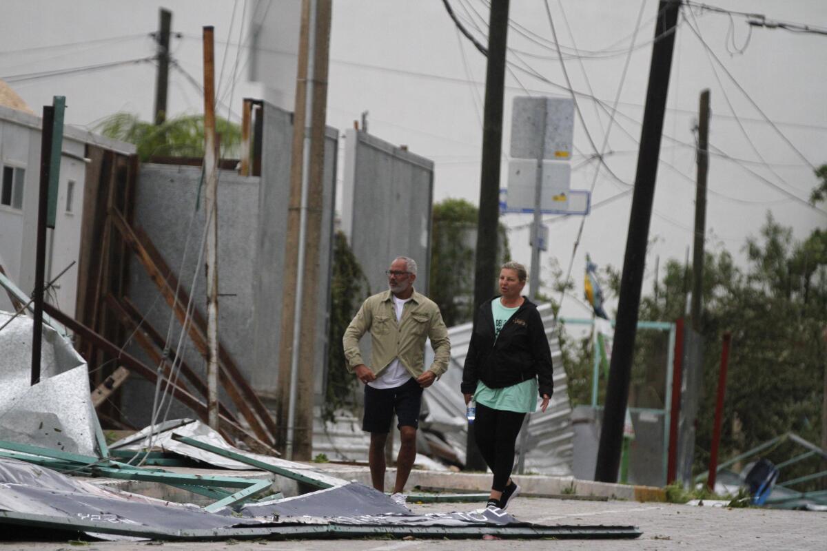 Dos turistas caminan entre los escombros en la calle después de que el huracán Zeta tocara tierra en Playa del Carmen, México