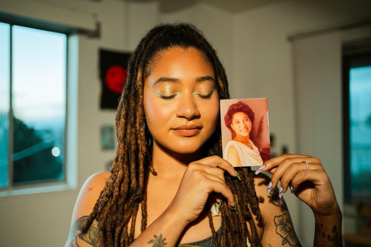 A woman with her eyes closed holds up a photo of her late mother.