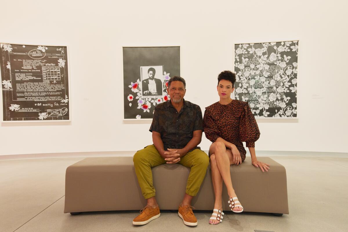 Sadie Barnette and her father Rodney sit in a gallery surrounded by FBI file documents turned into art