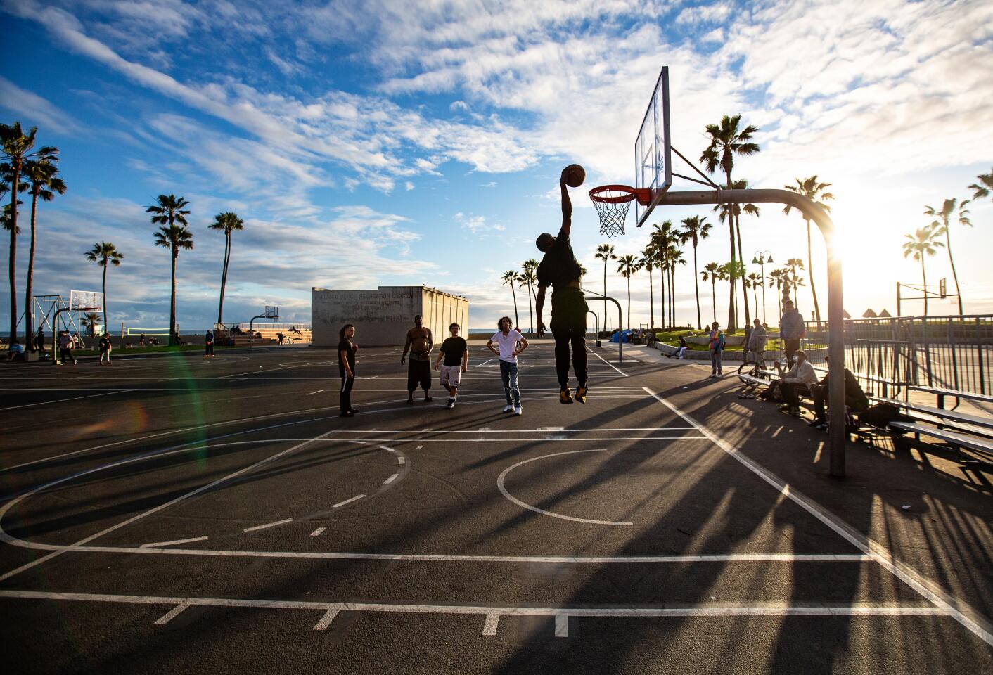 After playing a game of basketball, a group of guys watches as one of their friends dunks at Venice beach on Thursday.