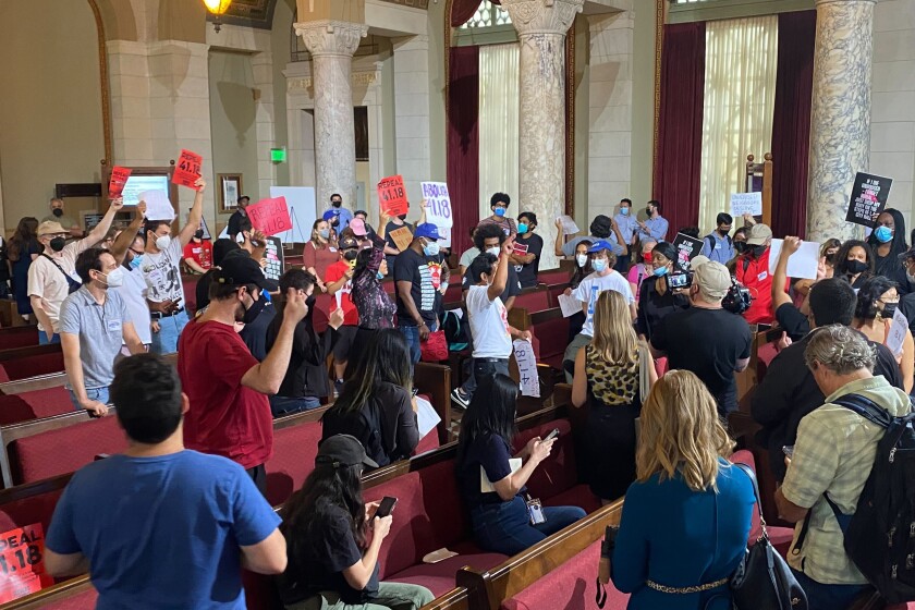 Homeless advocates carry signs as they disrupt the Los Angeles City Council meeting.
