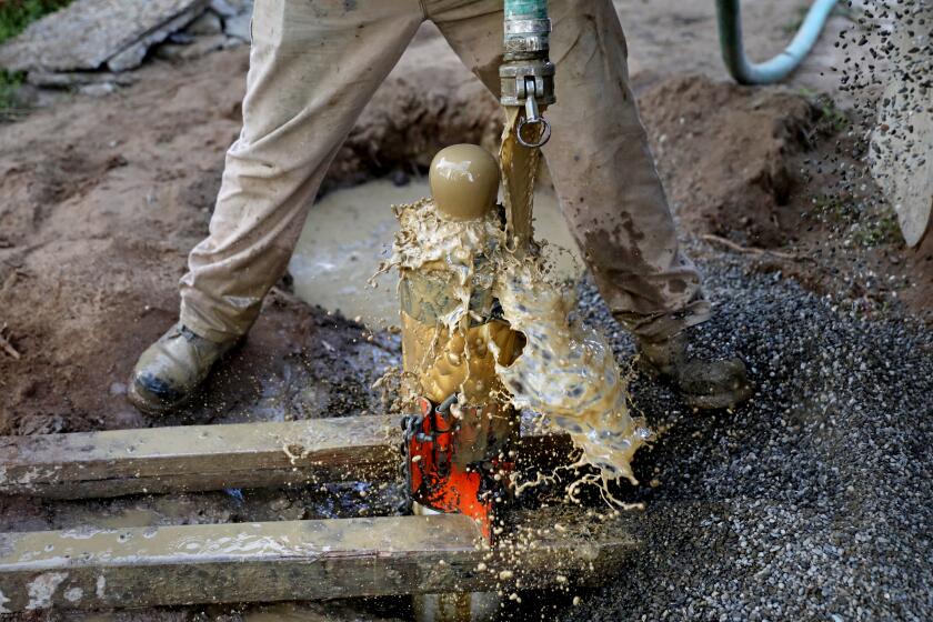 SANGER, CA - FEBRUARY 22: Julio Morales, foreman for H&B Drilling and Sons, places gravel around a newly drilled 240-ft water well, on the property of Tom Cook, 55, not shown, homeowner, along Central Ave., in the Tombstone neighborhood, unincorporated Fresno County, on Wednesday, Feb. 22, 2023 in Sanger, CA. Cook has an agency transport non-potable water to a 2500 gallon tank located on his property. Tom had a 70-ft well that went dry in Aug. 2022, the same year he purchased the home. He spent around $30,000 for the new well. In the community of Tombstone in Fresno County, residents' wells have continued going dry during the drought as nearby farms have heavily pumped groundwater, drawing down the water levels. Residents have lost access to water and are now depending on tanks and deliveries of water by truck. A potential solution for the area would involve connecting to water pipes from nearby Sanger, but progress has been slow. (Gary Coronado / Los Angeles Times)