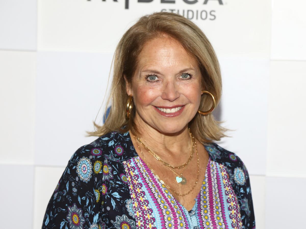 A woman with blond hair and hoop earrings smiles for the camera