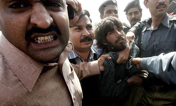 Pakistani police officers arrest one of the alleged gunmen at a police training school on the outskirts of Lahore, Pakistan. After the daylong siege, Pakistan's Interior Ministry announced that four of the gunmen had been killed and a fifth was arrested.