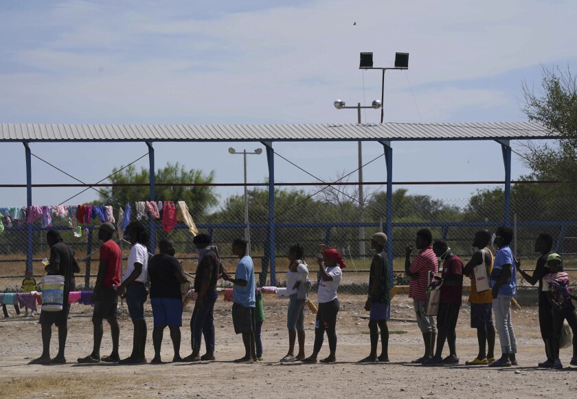 People wait in line near clothes hanging to dry