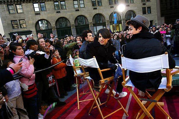 While the Jonas Brothers crisscrossed New York City to work the TV talk-show circuit, an army of young female fans awaited them at every stop. Between the fan camps, text-message updates jammed the satellite waves. Outdoors for an appearance on CBS' "The Early Show," the brothers -- from left, Kevin, Joe and Nick -- acknowledge the crowd. Related: The Jonas Brothers: It's full scream ahead