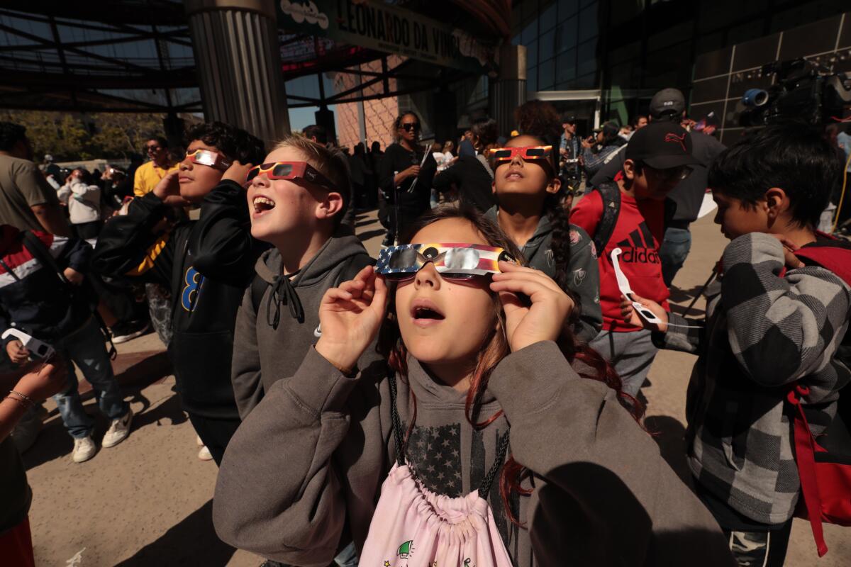 Crowds with protective eyewear gathered at the California Science Center to view the partial solar eclipse on Monday.