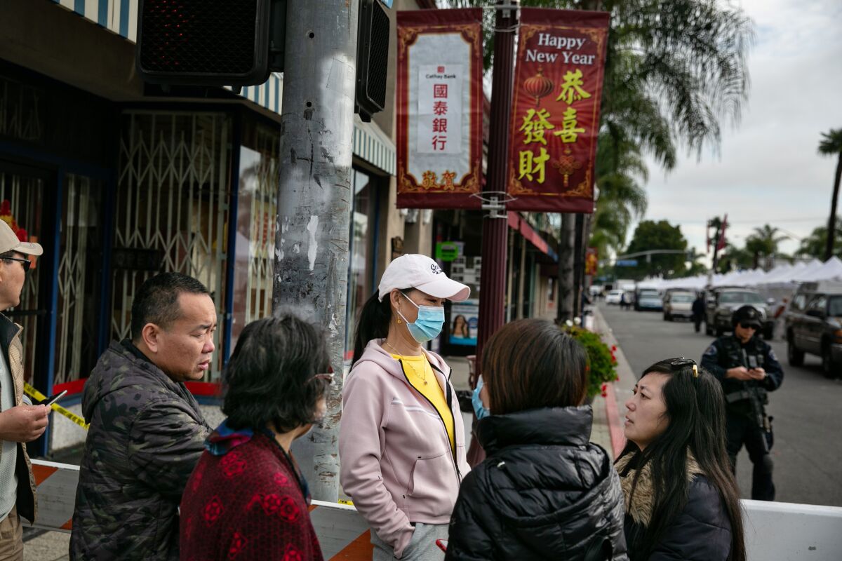 People stand below Happy New Year signs displaying Chinese characters