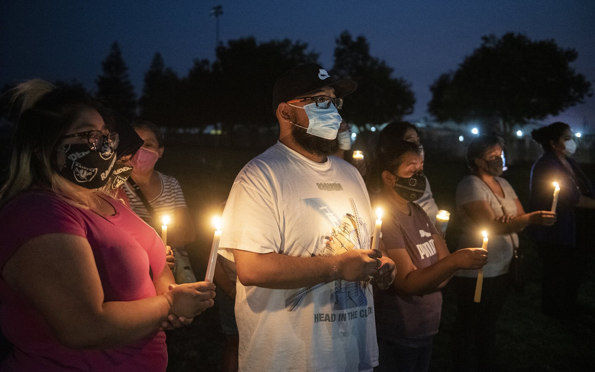 Foster Farms employee Kevin Vera, 28, of Livingston, center, attends a community candlelight vigil in Livingston, Calif.
