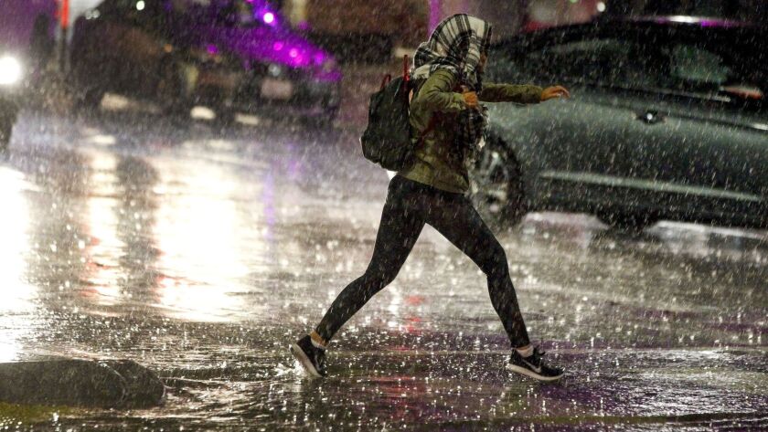 A woman runs across B Street while on 6th Avenue during a heavy downpour in downtown San Diego on Dec. 6, the city's wettest day of 2018. A total of 1.8 inches of rain fell that day.