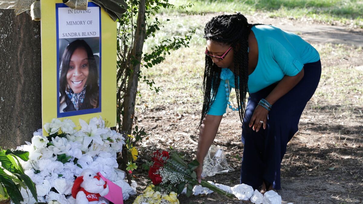 A woman places a bouquet of roses at a memorial for Sandra Bland, who died in a Texas jail after a contentious traffic stop.