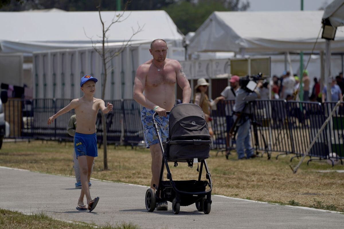 A Ukrainian refugee walks with his children at a camp in Utopia Parkin Mexico City on Monday.