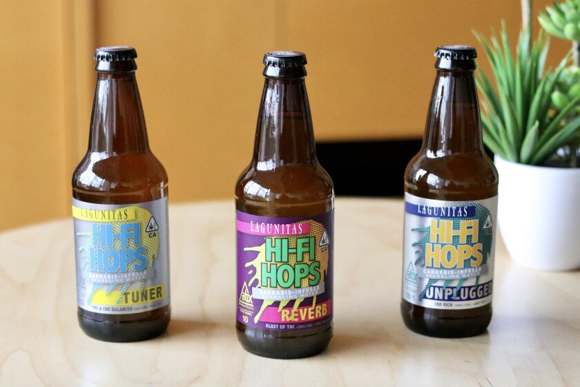 Three bottles with colorful labels sitting on a table.