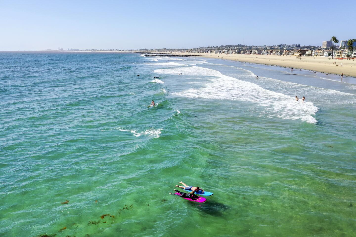 An aerial view of a few surfers and beach-goers enjoying a nice day at the beach despite Gov. Gavin Newsom's hard closure, which is still in place in Newport Beach.