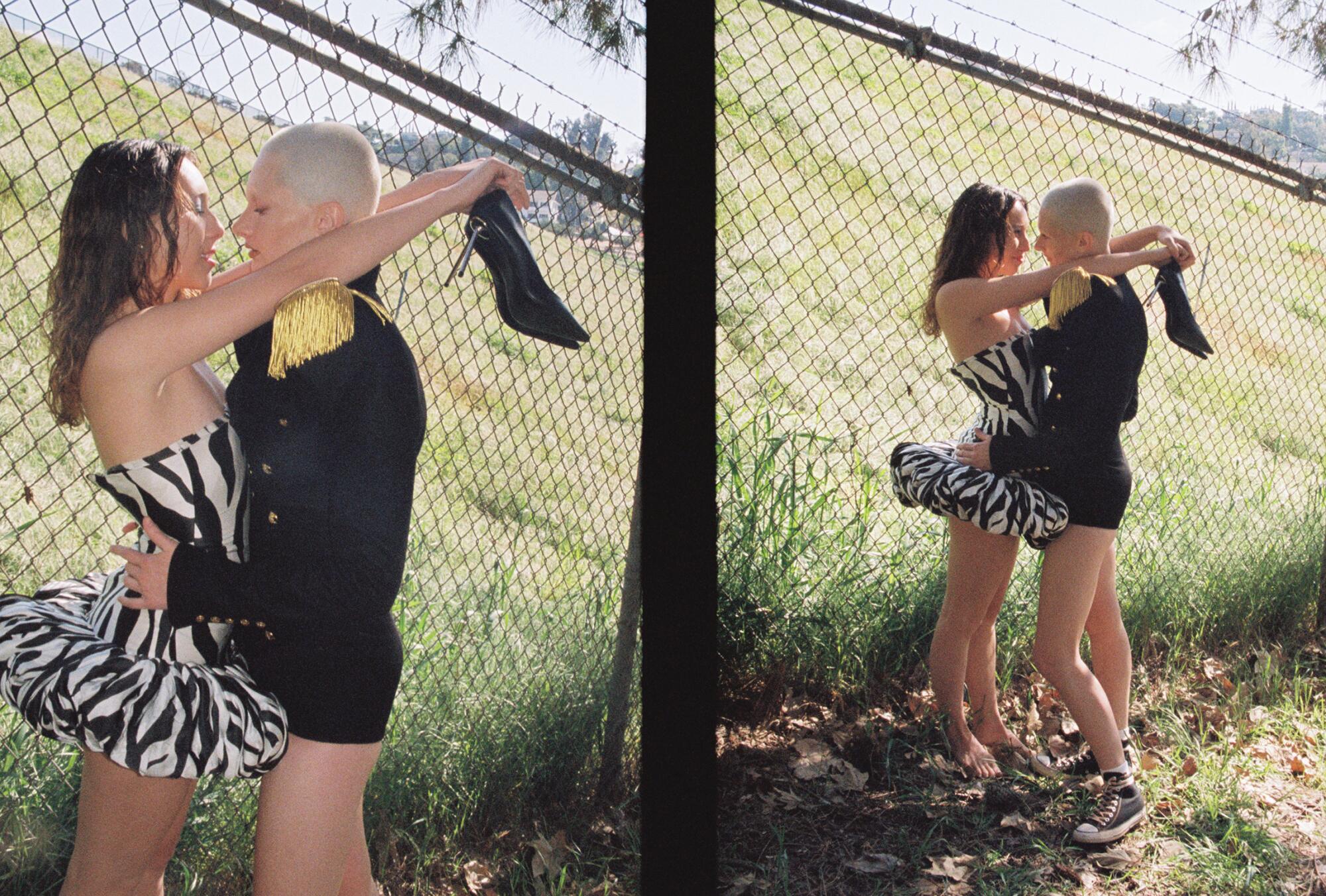 A couple embraces by a chain link fence.