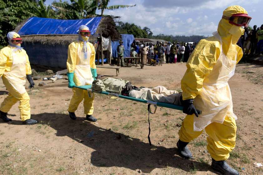 In November 2014, health workers in protective suits carry a patient suspected of having Ebola to a treatment center in Guinea.