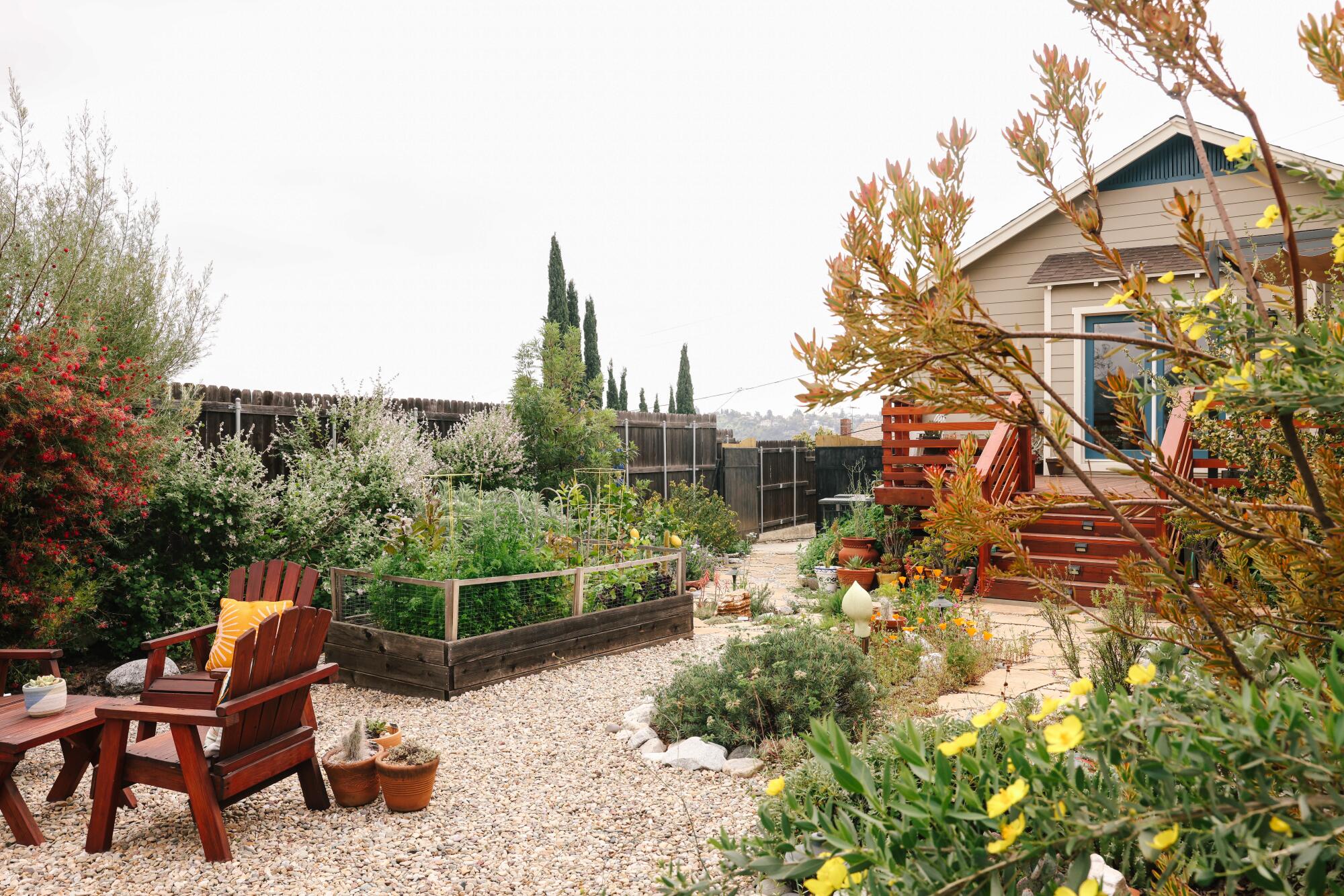 A backyard with raised beds, gravel and table and chairs