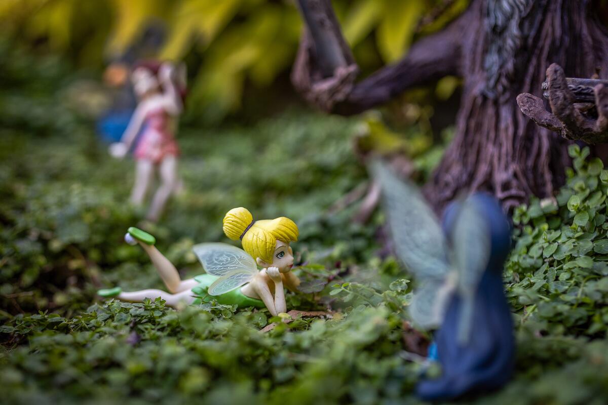 Tinker Bell is nestled in a green forest scene with her fellow Pixie Hollow fairies.