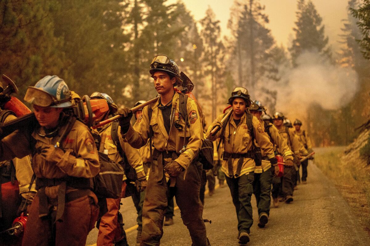 Firefighters march down a mountain road