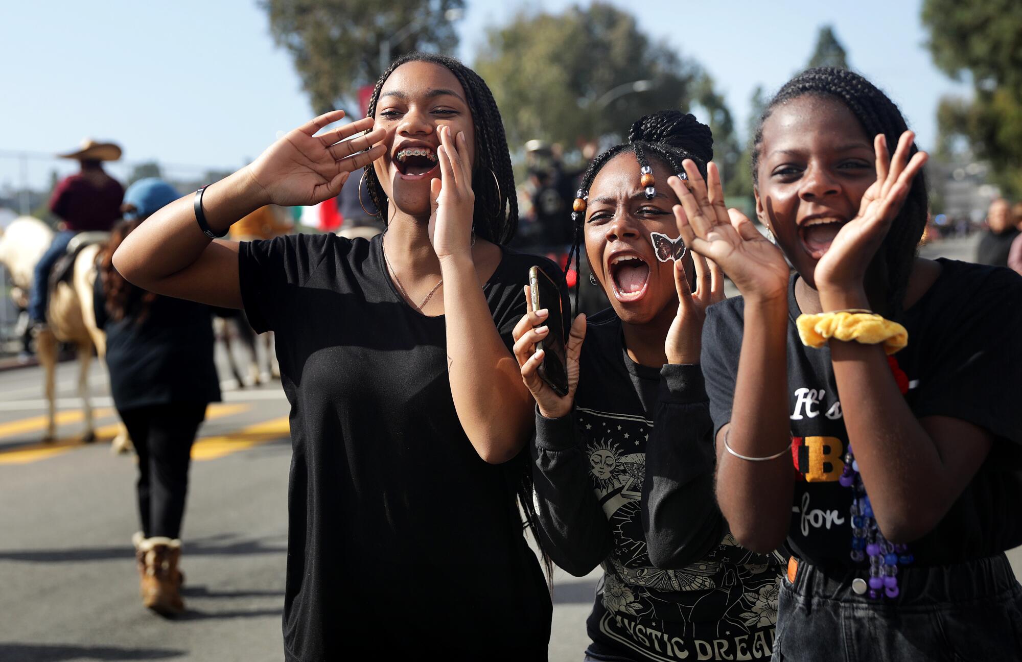 Three girls cheer on a friend participating in the 38th Annual Kingdom Day Parade in Leimert Park