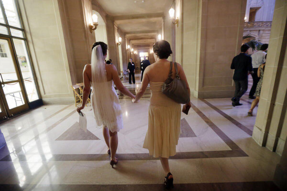 Cynthia Wides and Elizabeth Carey hold hands as they walk to be married at City Hall in San Francisco Saturday.