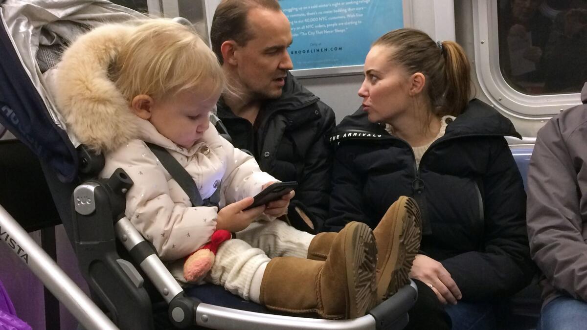 A child plays with a smartphone while riding the subway in New York.