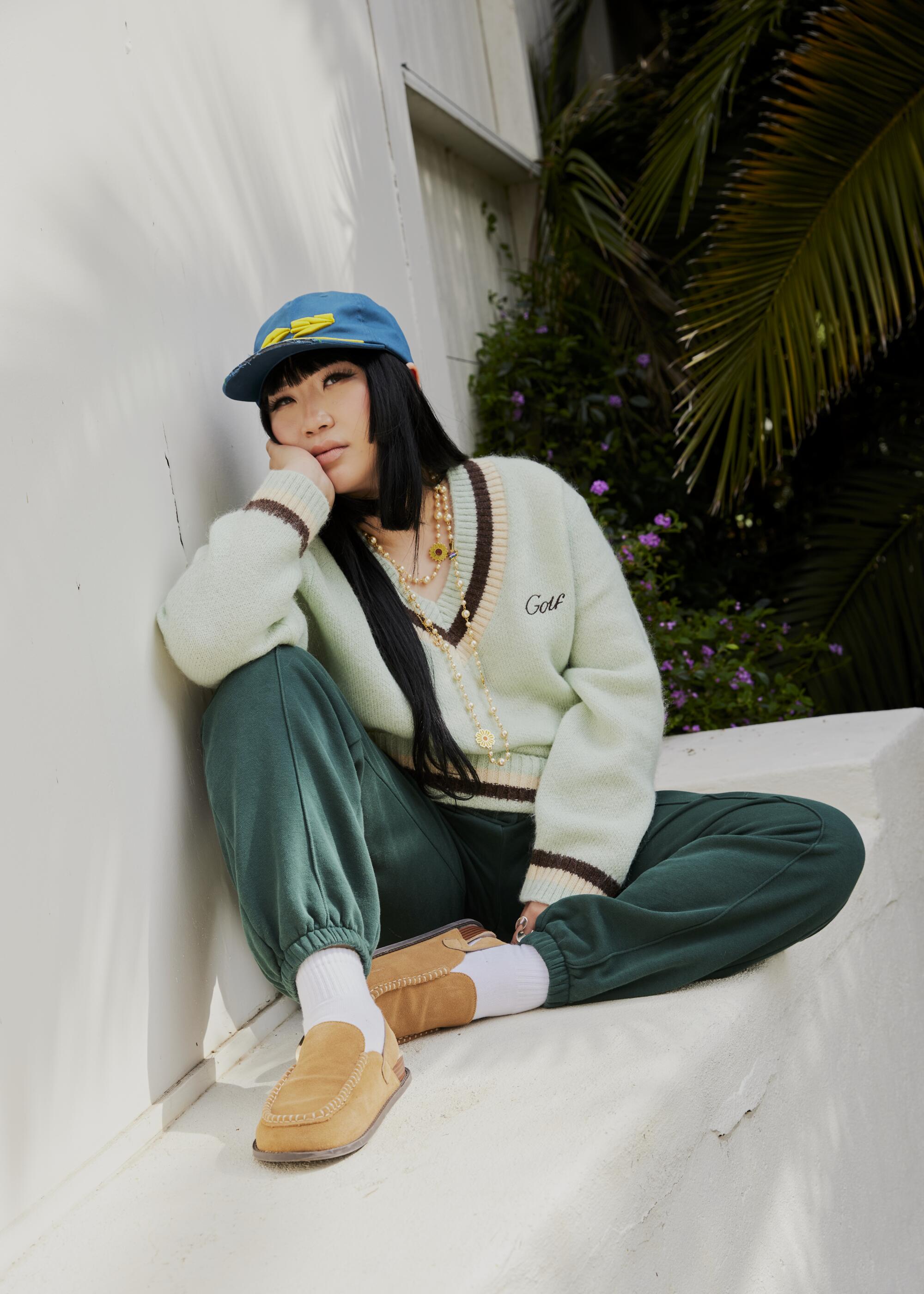 Stylist Jess Mori wears an all-green outfit and blue cap.