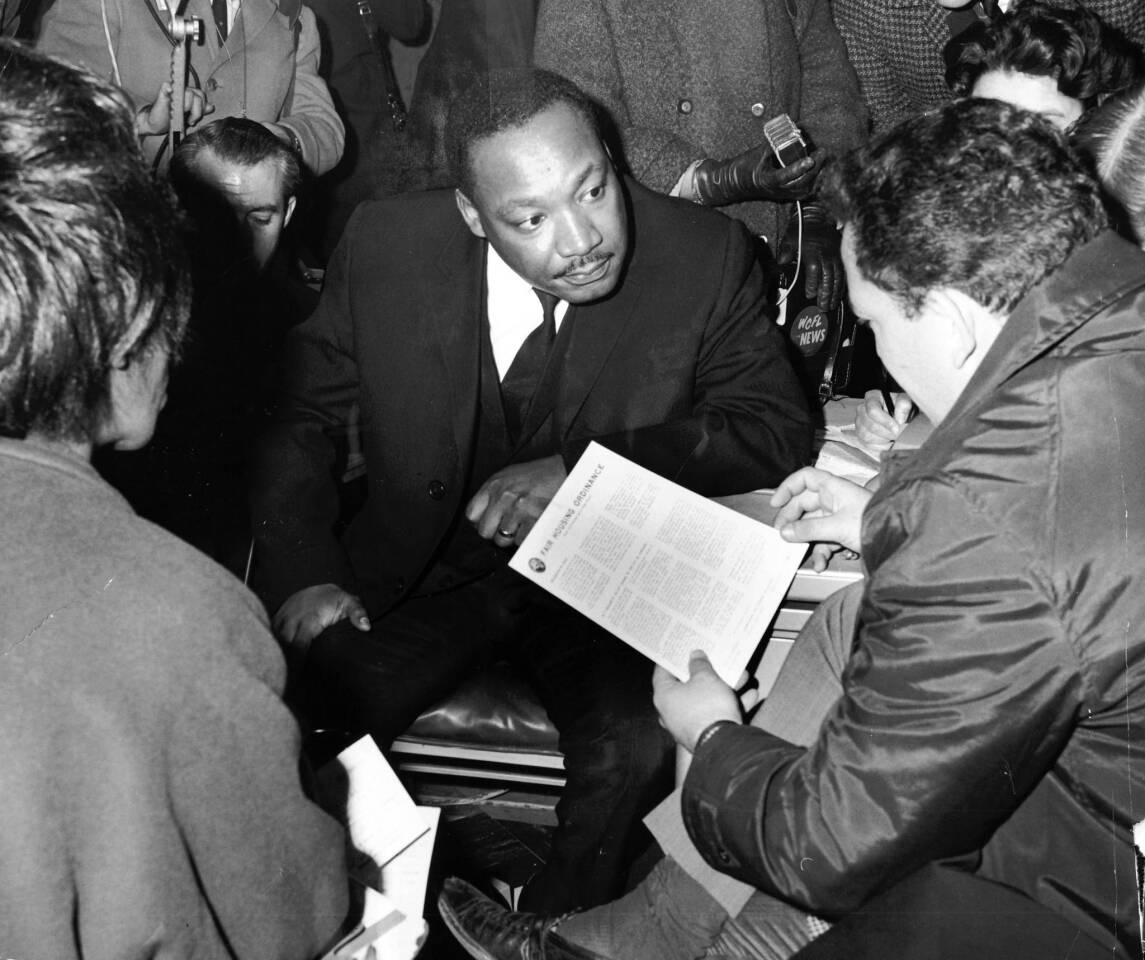 The Rev. Martin Luther King Jr., center, appears intense as he discusses fair housing with Gilbert Balin, of G. Balin Inc. real estate agents in Chicago on Nov. 3, 1966.