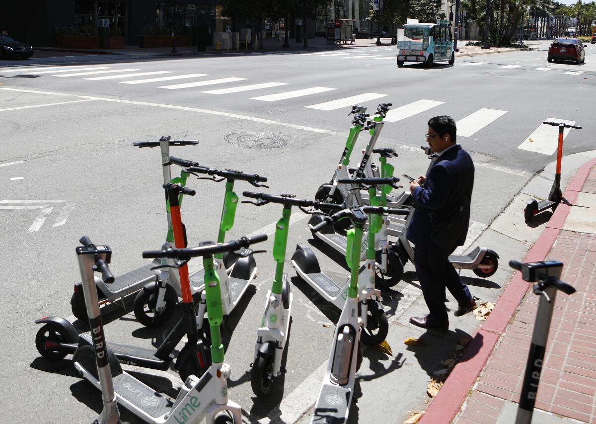 Bird and Lime scooters lined up on Broadway in downtown San Diego in May 2022. 