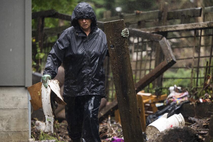A resident clears debris from a yard after the San Lorenzo River overflowed and flooded the Felton Grove neighborhood in Felton, California, US, on Wednesday, Jan. 11, 2023. California faces more drenching rain, as concerns about drought have been replaced by fears of flooding thats killed at least 14 people, closed highways and sent residents fleeing for their lives. Photographer: Nic Coury/Bloomberg via Getty Images