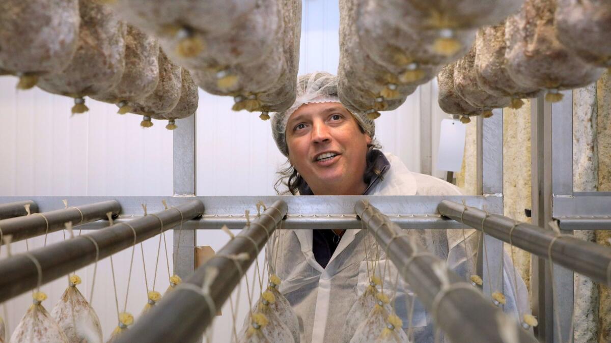 Oliviero Colmignoli inspects curing salamis in one of the many drying rooms at his Olli Salumeria factory in Oceanside.