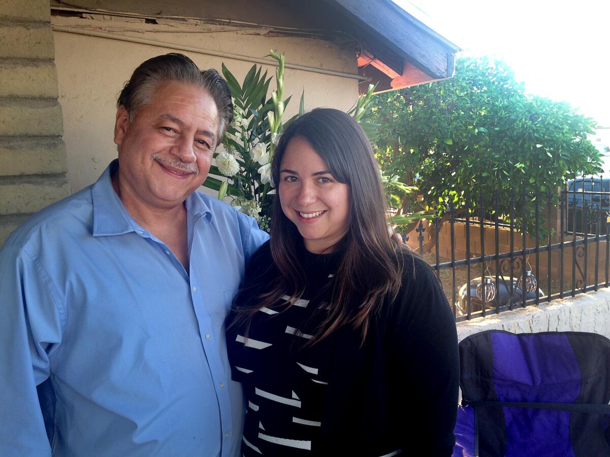 Mark Urquiza, his arm around daughter Kristin, smiles for a photo outdoors. 