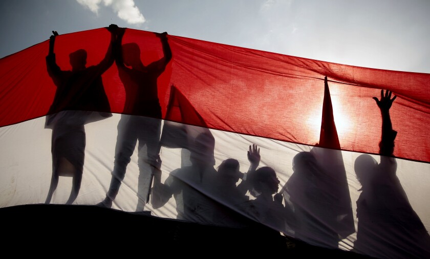People are silhouetted behind an oversized flag.
