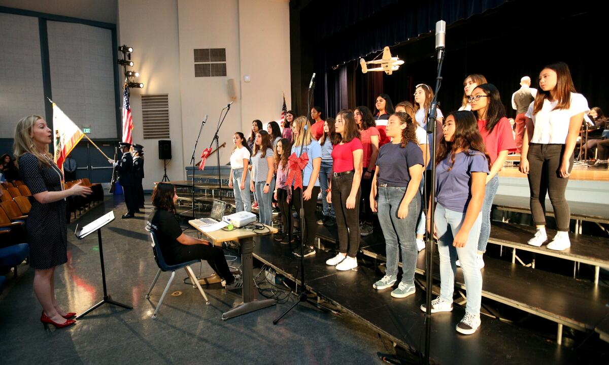 Music instructor Rebecca Southward, left, leads the Advanced Choir and Mixed Choir at the annual Wilson Middle School's annual Veterans Day Assembly in Glendale on Thursday.