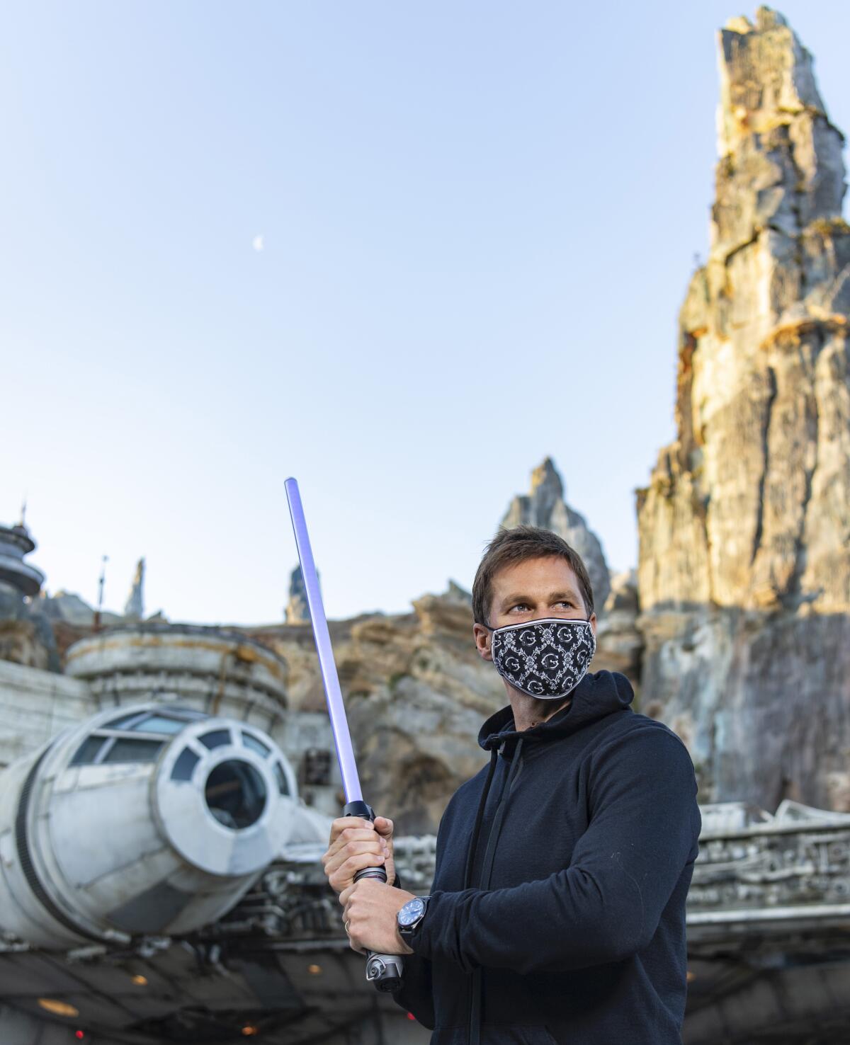 In this photo provided by Walt Disney World, NFL star Tom Brady visits Star Wars: Galaxy's Edge inside Disney's Hollywood Studios at Walt Disney World Resort in Lake Buena Vista, Fla., Monday, April 5, 2021. A mask-wearing Brady visited the Star Wars-themed section of Walt Disney World with his family and friends, two months after he led the Bucs to a Super Bowl win against the Chiefs. (Matt Stroshane/Disney World via AP)