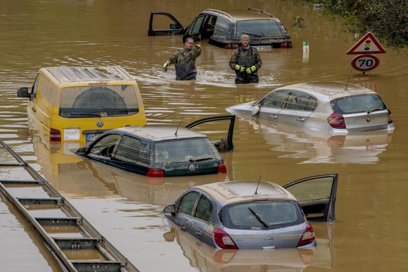 FILE - In this file photo dated Saturday, July 17, 2021, people check for victims in flooded cars on a road in Erftstadt, Germany, following heavy rainfall that broke the banks of the Erft river, causing massive damage. The German government on Tuesday Aug. 10, 2021, has agreed to provide 58 billion euros (dollars 68 billion US) to help rebuild regions hit by devastating floods last month. (AP Photo/Michael Probst, FILE)