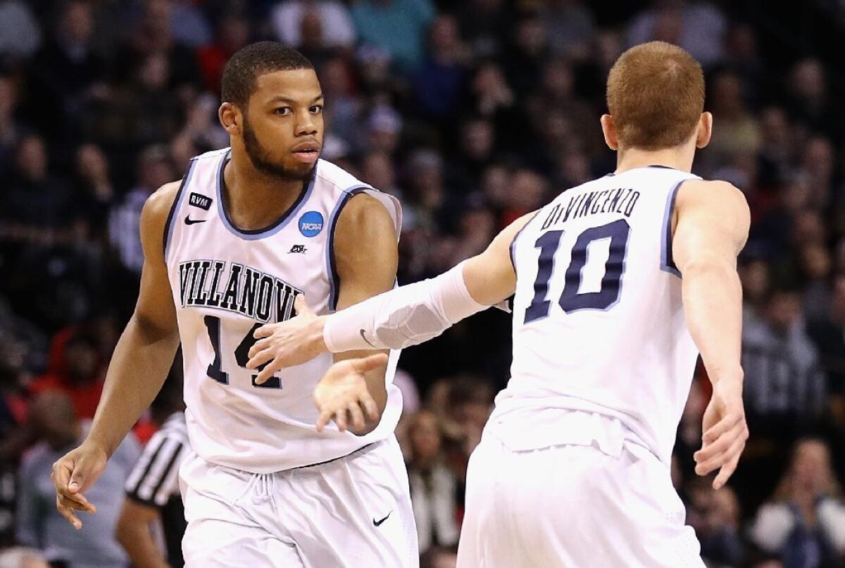 Omari Spellman (14) high-fives teammate Donte DiVincenzo during the second half of an Elite Eight game against the Texas Tech.