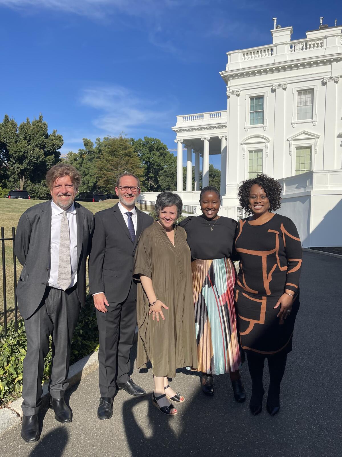 Five people standing together in front of a building