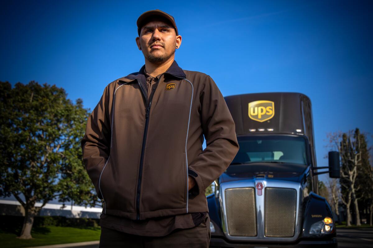 A UPS driver stands in front of his truck. 