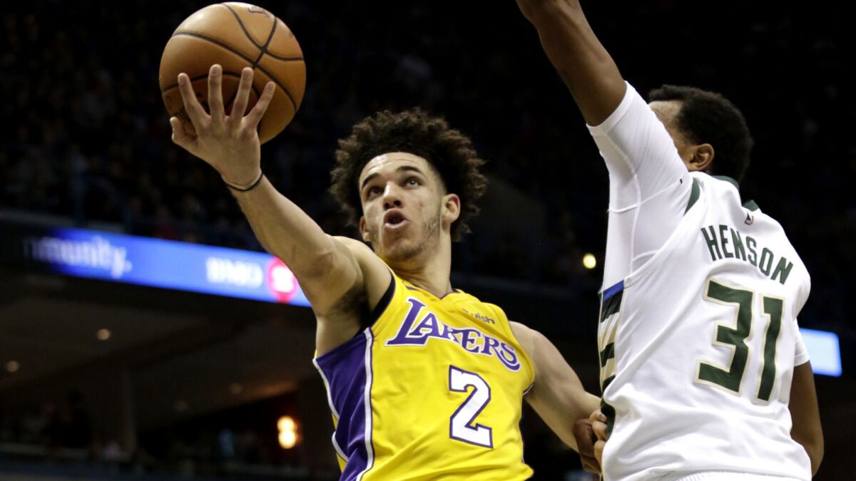 Lakers guard Lonzo Ball tries to slip past Bucks forward John Henson for a layup during the first half Saturday.