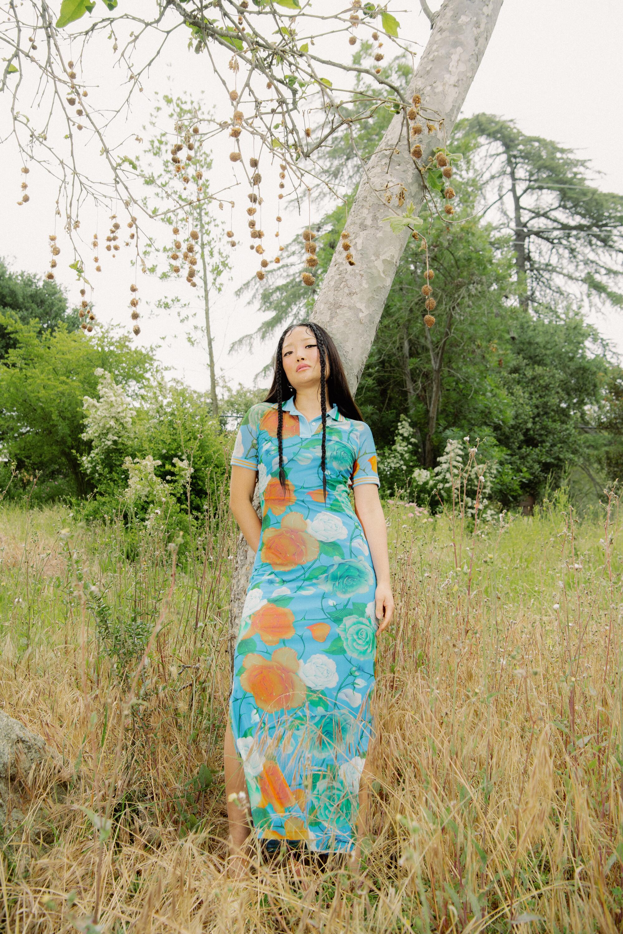 woman in a dress poses in front of a tree