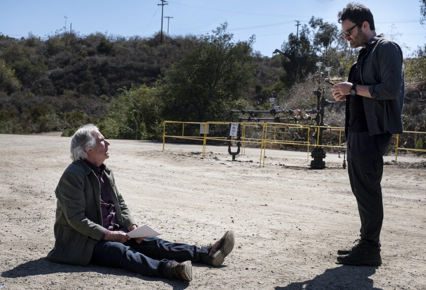 A man stands over another man sitting on the ground.