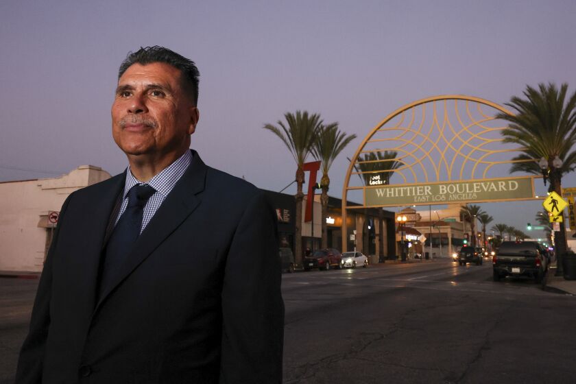 East Los Angeles, CA - September 29: L.A. County Sheriff candidate Robert Luna poses near a sign welcoming visitors to Whittier Boulevard in East Los Angeles, where he lived as a young child. As he stood near the iconic sign, members of the local community stopped to greet him. Photo taken in East Los Angeles, Thursday, Sept. 29, 2022. (Allen J. Schaben / Los Angeles Times)