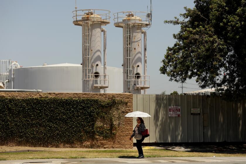 WILMINGTON-CA-JUNE 1, 2022: A pedestrian passes by Warren E&P on Anaheim Street in Wilmington on Wednesday, June 1, 2022 where earlier that morning, Communities for a Better Environment, Standing Together Against Neighborhood Drilling, and U.S. Congresswoman Nanette Barragan held a news conference to allege illegal oil drilling in Wilmington and demand the city of Los Angeles take action against oil operator Warren Resources. (Christina House / Los Angeles Times)